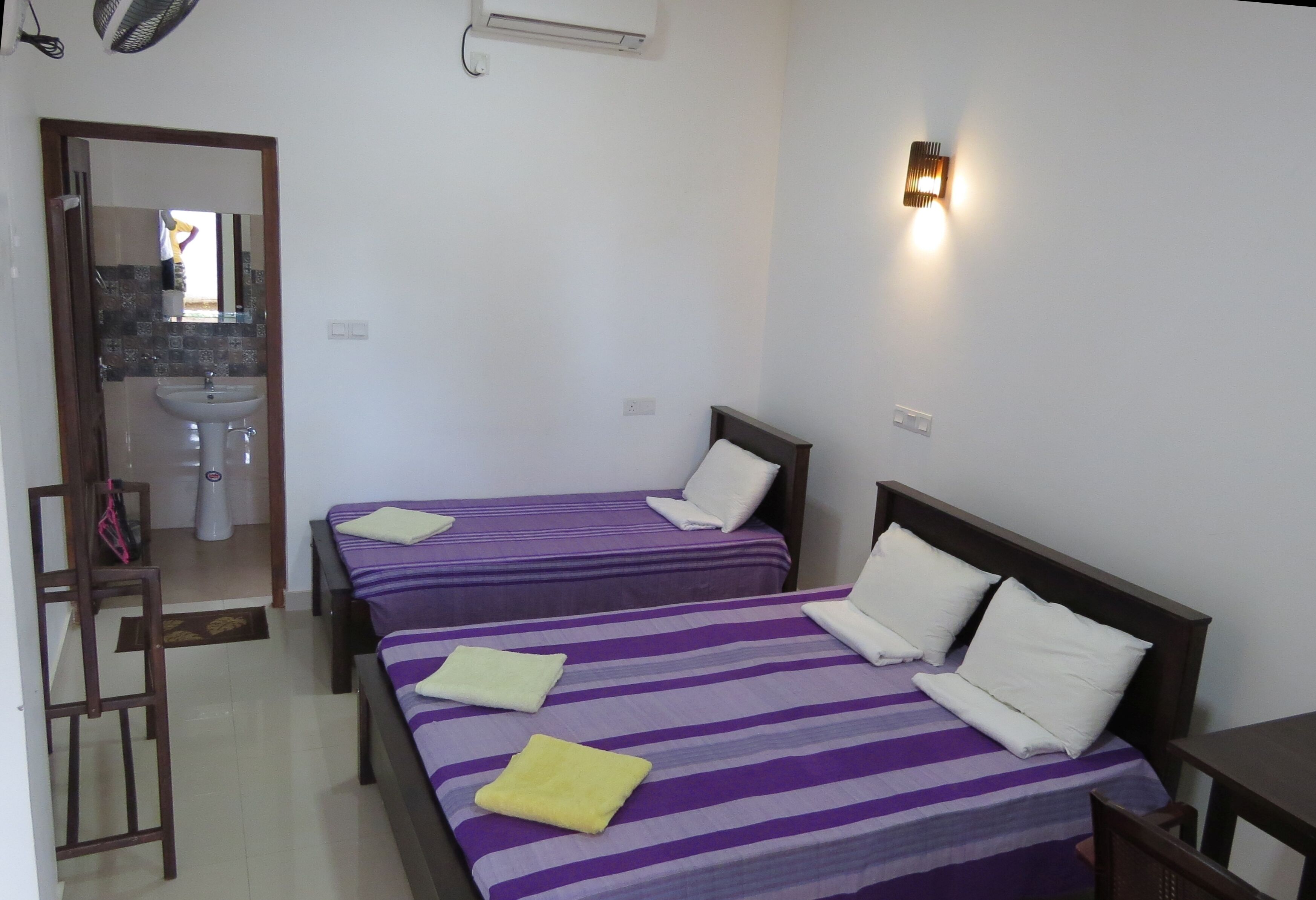 Una habitación de hotel con dos camas, un baño y una mesita.