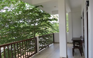A balcony with a wooden railing, a small table, and chairs. - Sailors Mirissa (Mirissa)