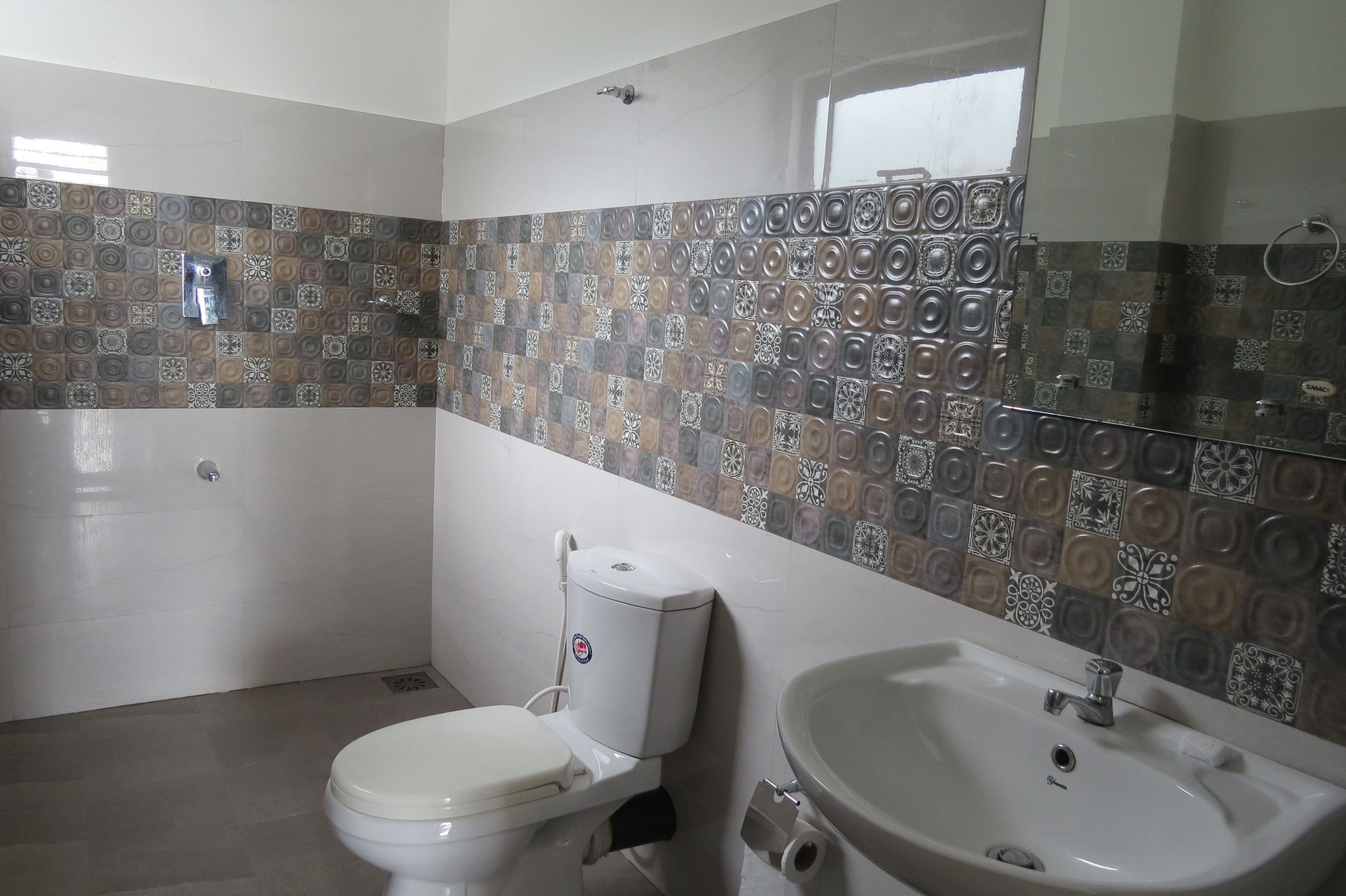 A bathroom with a toilet, sink, and patterned tiles on the walls.