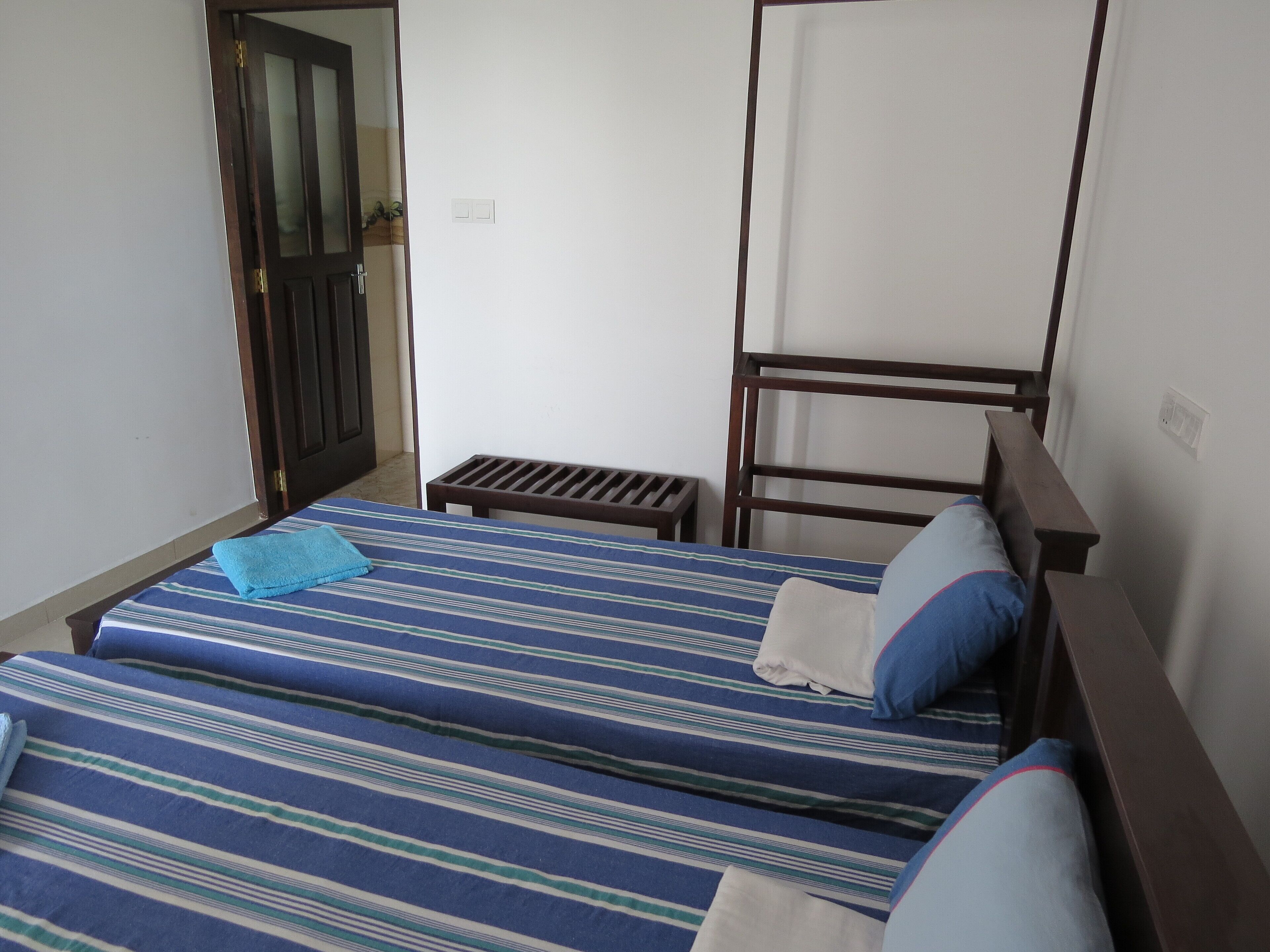 A room with two beds, a wooden headboard, a small table, and a door.