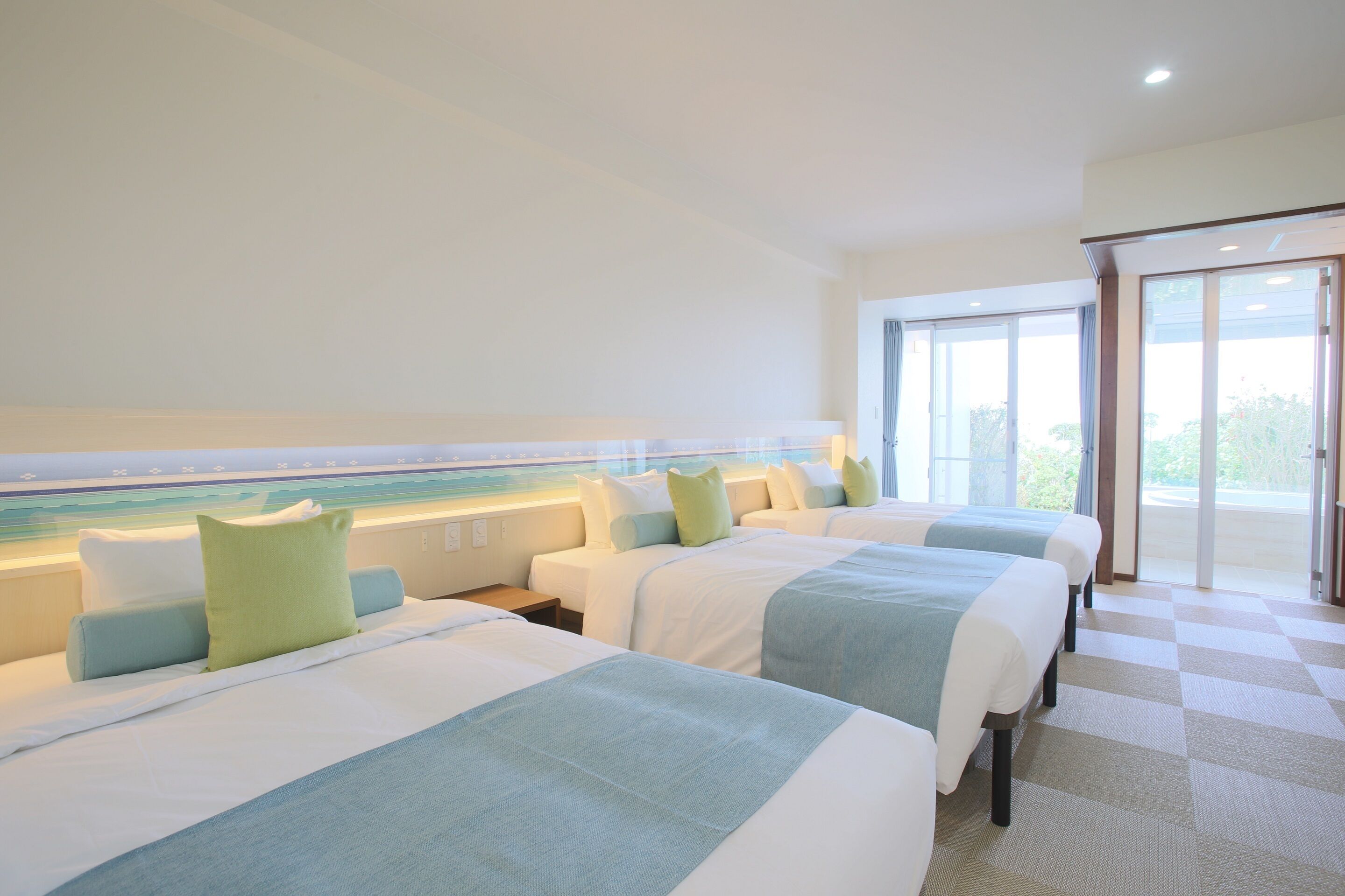 Ein Hotelzimmer mit vier Betten, einem großen Fenster und einem Schachbrettmuster-Boden.