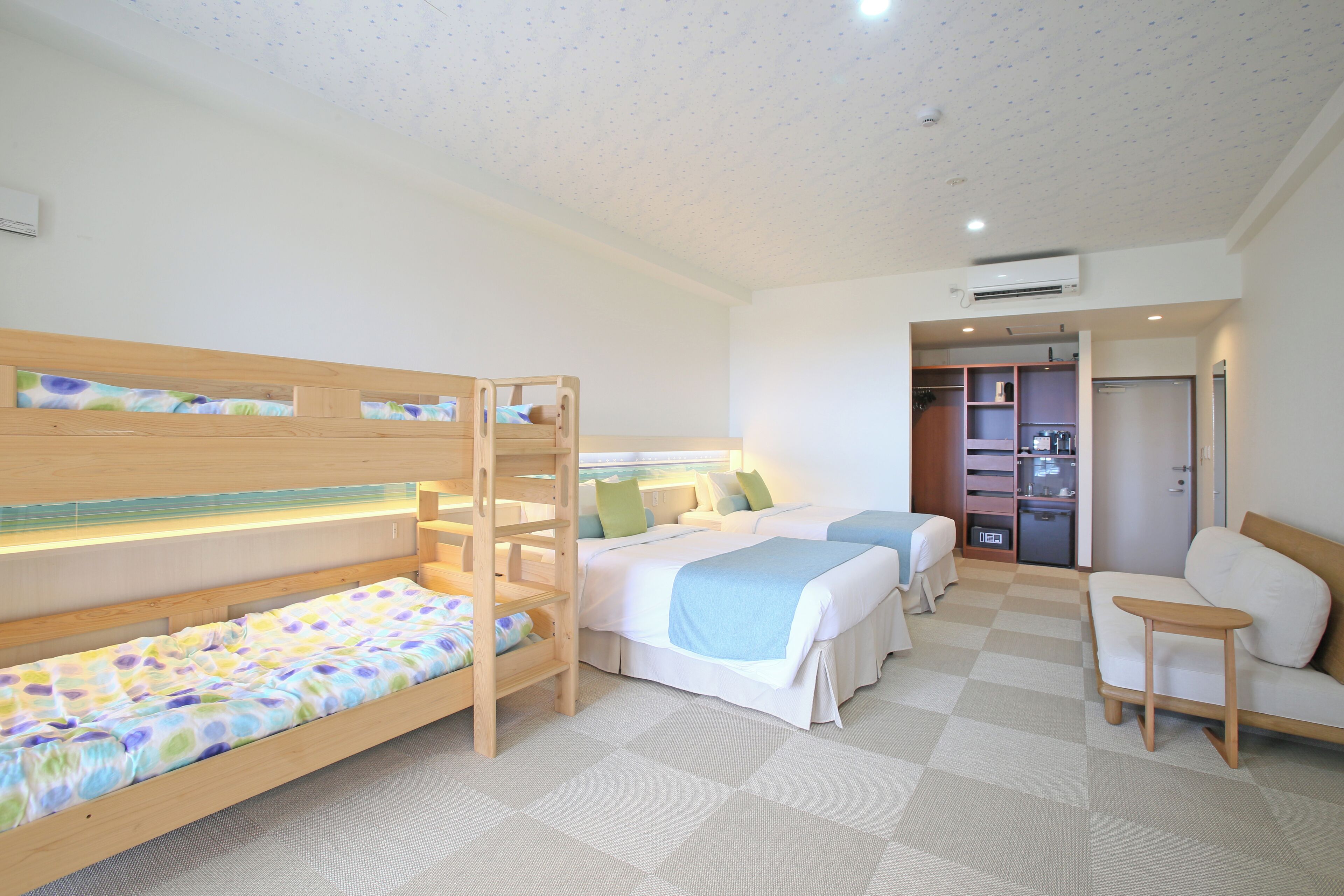 Ein Schlafzimmer mit Etagenbetten, einer Schlafcouch, einem kleinen Tisch und einem Kleiderschrank.