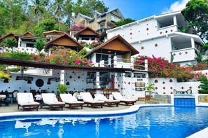 A poolside area with lounge chairs, a bar, and a pool.