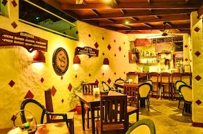 A restaurant with wooden tables and chairs, a bar area, and walls decorated with diamond patterns.