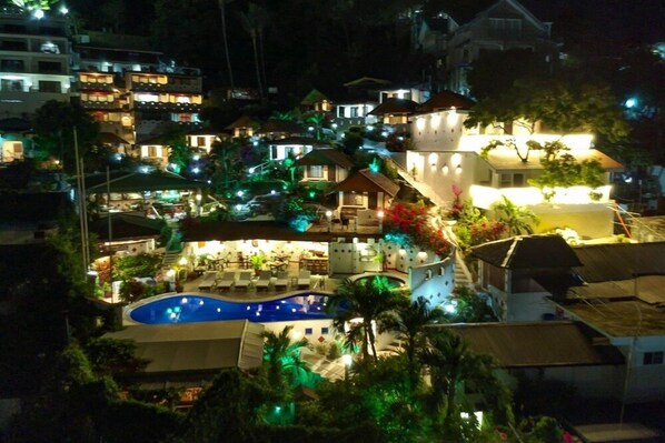 A resort with a swimming pool, multiple buildings, and lush greenery.