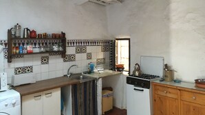 Una cocina con salpicadero de azulejos, estufa, pileta y muebles de madera.