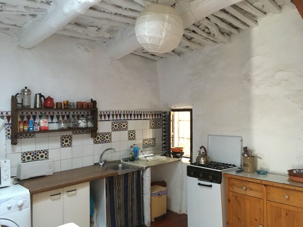 Una cocina con salpicadero de azulejos, estufa, pileta y muebles de madera.