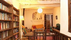Una sala acogedora con chimenea, una estantería y un comedor.