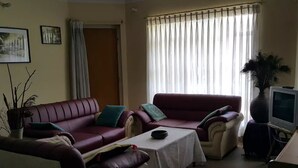 Una sala de estar con dos sofás de cuero, una mesa de centro, un televisor y una planta en maceta.