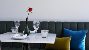 Une table à manger ornée d’un vase contenant une seule rose, de deux verres à vin et d’une assiette avec des couverts.