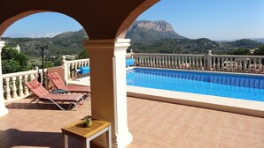 A pool area with a view of mountains, lounge chairs, and a small table. - Spacious villa, close to Denia, Pool 10m x 5m, great views, A/C, fast wifi 500mb (Alicante)
