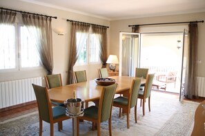 A dining area with a wooden table, six chairs, and a chandelier.