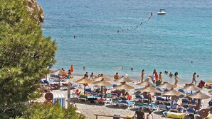A beach with sun loungers and umbrellas, a boat in the water, and people swimming. - Spacious villa, close to Denia, Pool 10m x 5m, great views, A/C, fast wifi 500mb (Alicante)