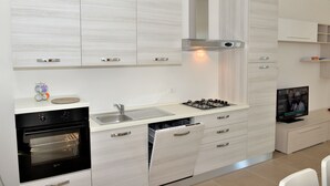 A modern kitchen with a built-in oven, a gas stove, a dishwasher, and a TV. - Blue apartment (Rodi Garganico)