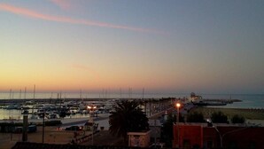 A marina with boats docked, a promenade, and a beach area. - Blue apartment (Rodi Garganico)