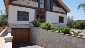 Een modern huis met een stenen gevel, een houten poort en een aangelegde tuin.
