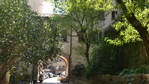 A cobblestone street flanked by trees and stone walls, leading to a building with arched windows. - NEW APARTMENT in the heart of Citta 'Alta (Bergamo)