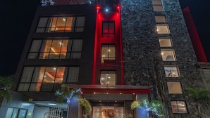 Ein Hotel mit Steinfassade, roten Akzenten und einem sichtbaren Eingang mit Stufen.