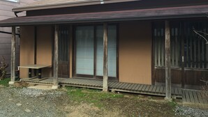 A house with a covered porch, a sliding glass door, and a small outdoor table.