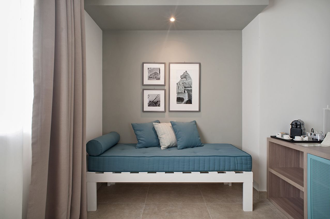 Una habitación pequeña y acogedora con una cama individual, una mesita con cafetera y tres cuadros en la pared.