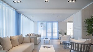 Una sala de estar moderna con un sofá, sillones, una mesa de centro y una mesa de comedor.