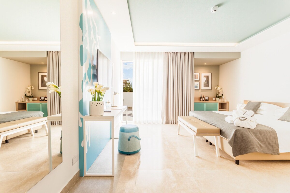 A modern hotel room with a large bed, a desk, and a seating area.