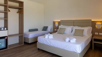 A hotel room with two beds, a wardrobe, a bedside table, and a nightstand.