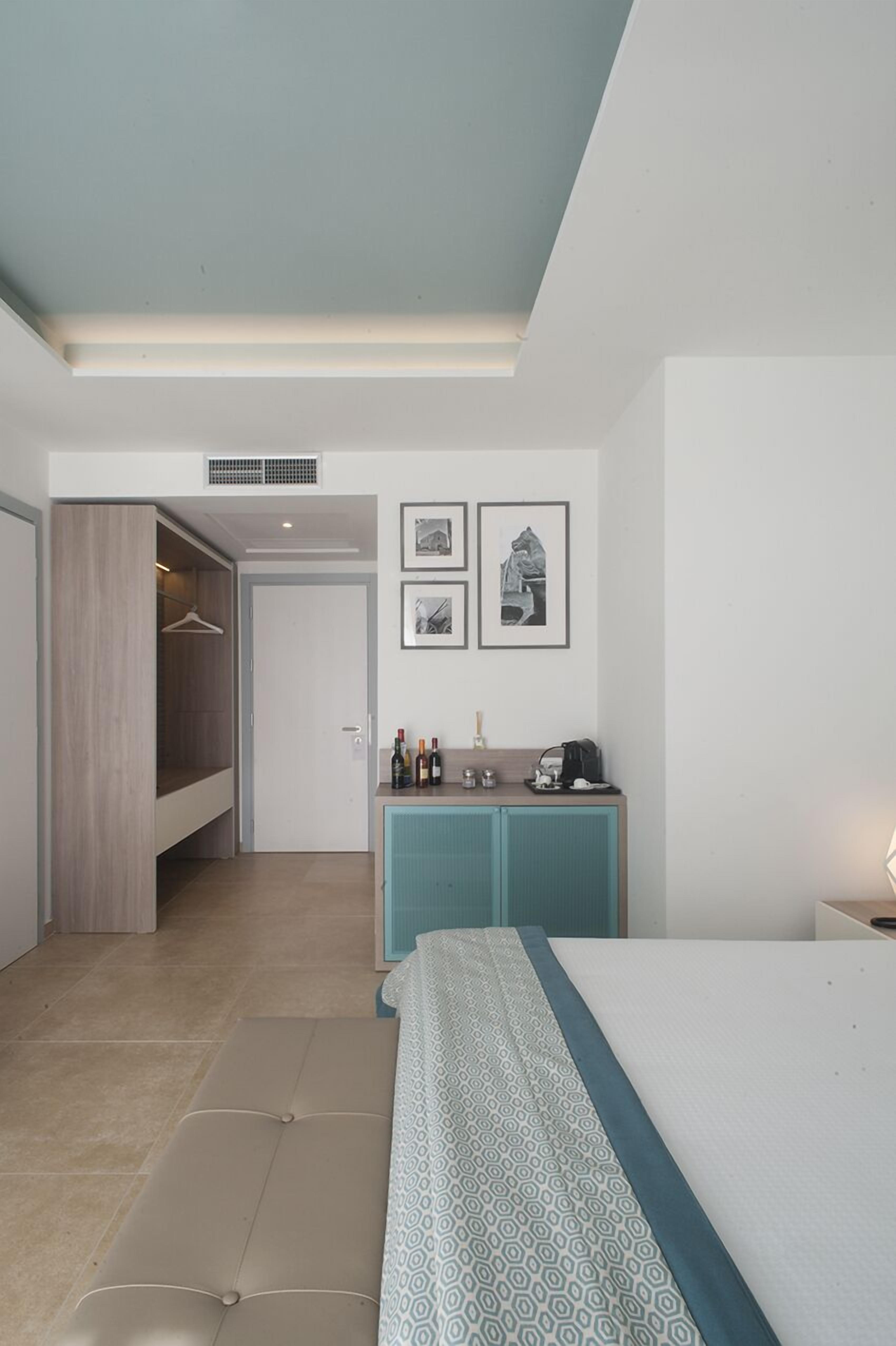 A modern bedroom with a bed, a wardrobe, a small kitchenette, and a bathroom.