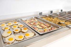 A buffet with various breakfast options including eggs, bacon, and scrambled eggs.