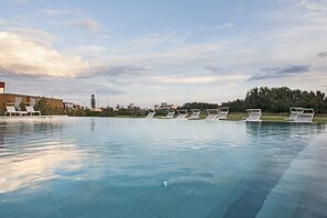 A swimming pool with lounge chairs and a building in the background.