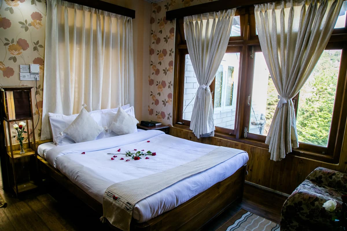 A neatly made bed with white linens and a floral pattern on the wall.