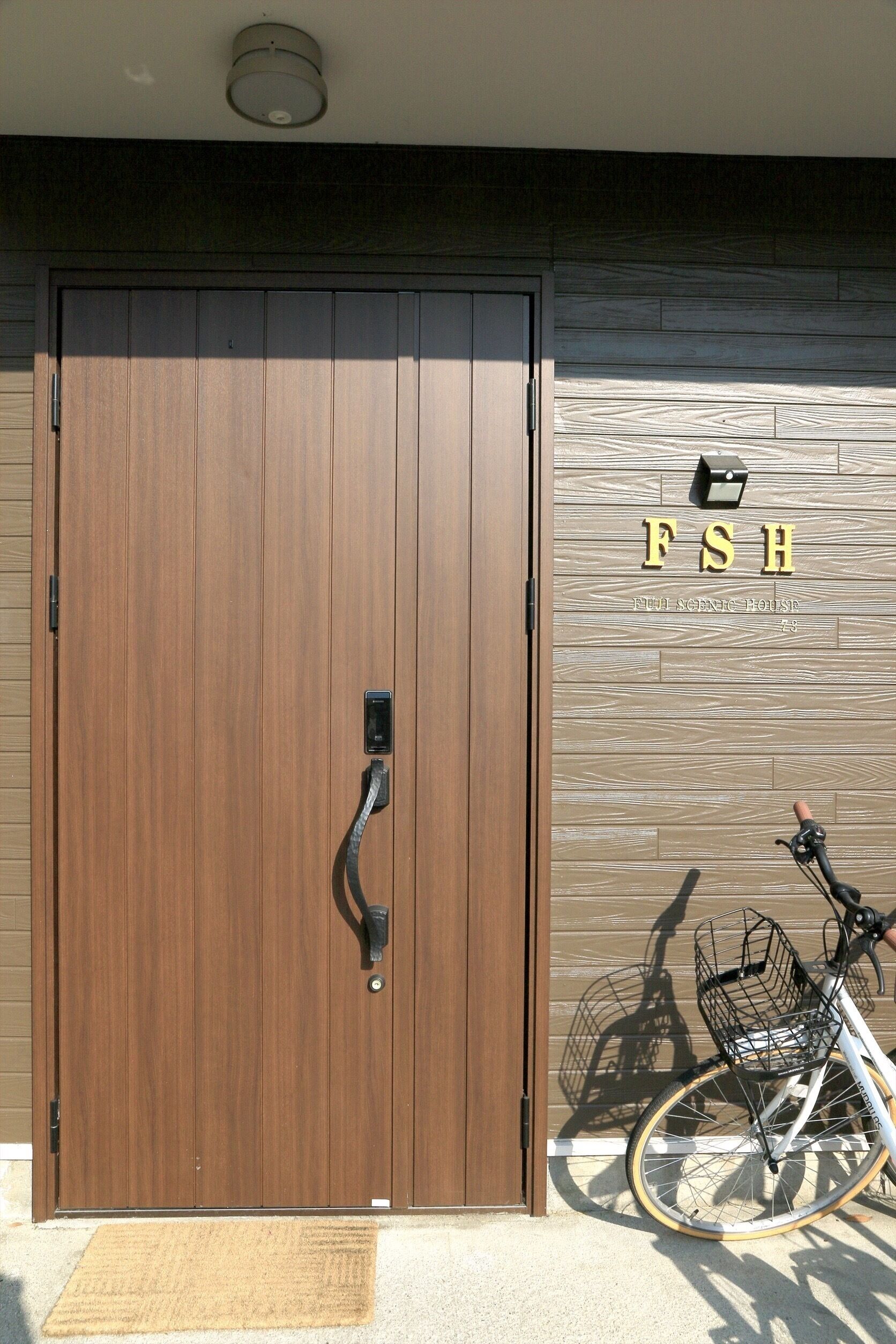 Uma porta dupla de madeira com maçaneta, um suporte para bicicletas e uma placa com a inscrição 'FSH'.