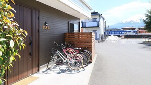 Edifici amb porta de fusta, bicicletes aparcades a l'exterior i vista a una muntanya.