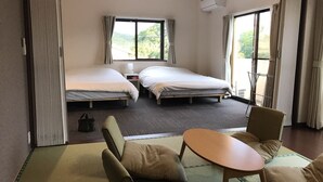 Habitació d'hotel amb dos llits, una taula petita i una cadira. Hi ha una finestra amb cortines i un aparell d'aire condicionat a la paret.