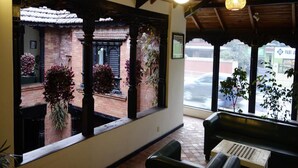 Una stanza con soffitto in legno, una panca, un tavolo e ampie finestre con piante.