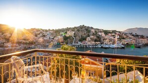 Un balcon offrant une vue sur une ville côtière, avec des bâtiments, un port de plaisance et des bateaux.