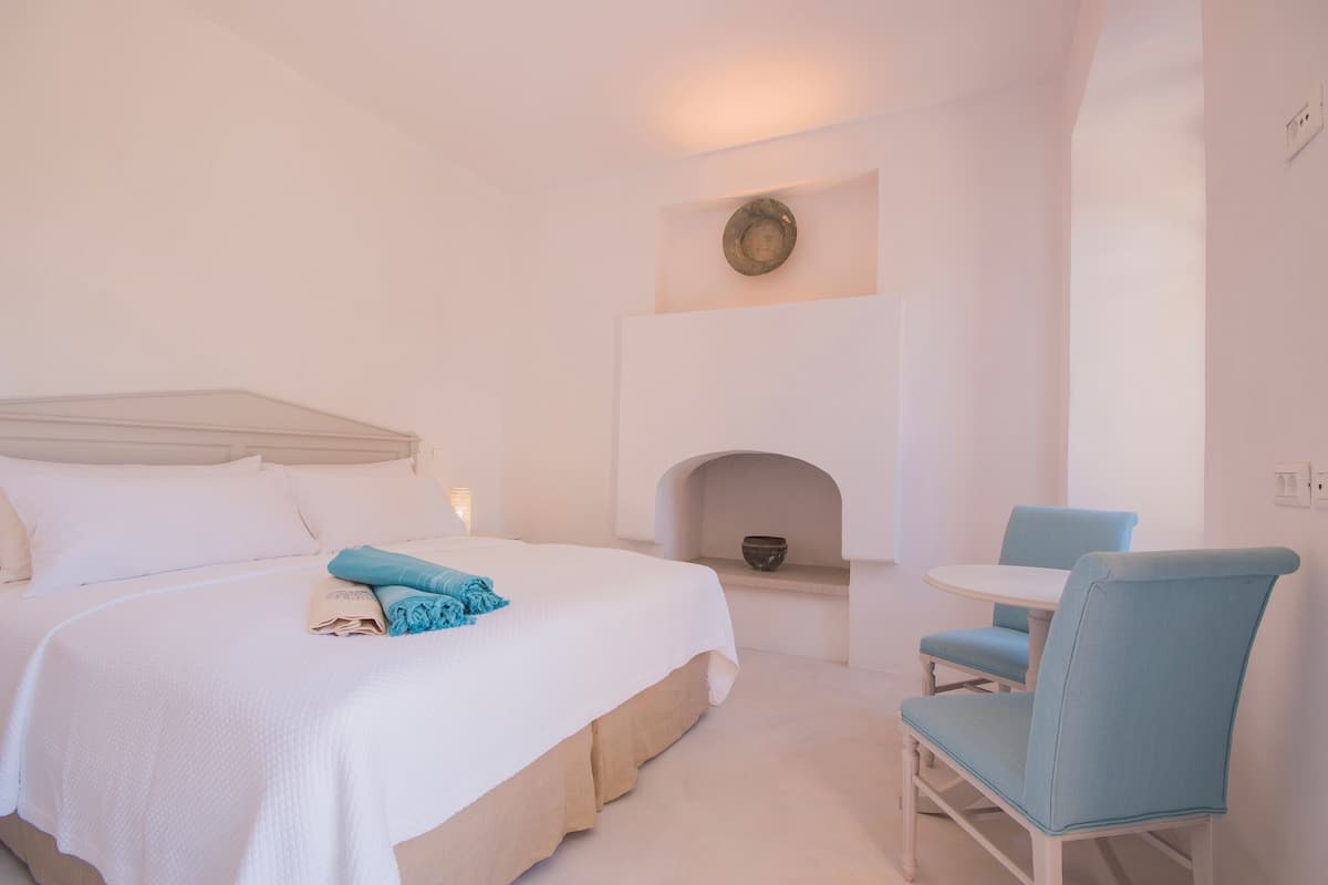 A hotel room with a bed, a small table, and a chair.