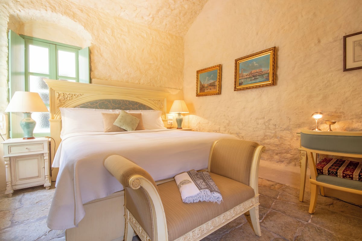A bedroom with a bed, bedside tables, a chair, and a small table with a lamp.