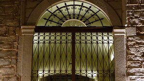 Une grande et somptueuse grille en métal, ornée de motifs complexes, encadrée par un arc en pierre.