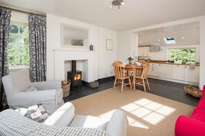 A cozy living room with a fireplace, checkered furniture, and a dining area with a table and chairs.