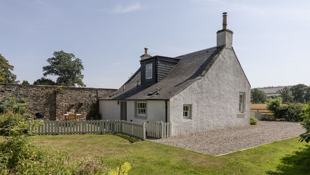 A stone house with a sloped roof, a gravel driveway, and a wooden fence. - GARDEN COTTAGE  - peaceful rural cottage in Scottish countryside (Denholm)