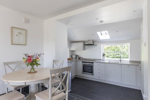 A modern kitchen with white cabinets, a built-in oven, and a window providing natural light.