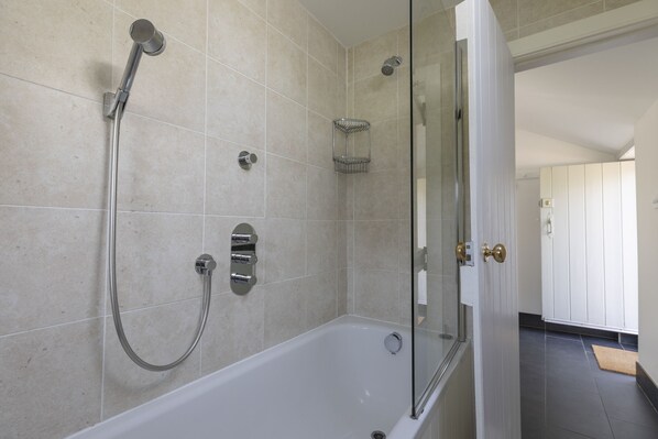 A modern bathroom with a glass-enclosed shower, a white bathtub, and a wall-mounted towel rack.