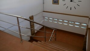 Una escalera con barandales de metal, un reloj fijado a la pared y un cuadro enmarcado.
