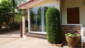 Una casa con puerta de cristal, un pequeño jardín y una maceta grande.