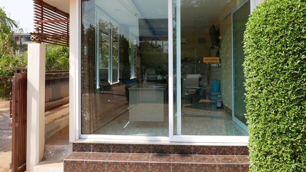 Un edificio moderno con puerta de cristal, un porche adoquinado y un arbusto bien cuidado.