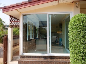 A modern building with a glass door entrance, a tiled porch, and a neatly trimmed bush.