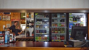 A bar area with a counter and a refrigerator stocked with various alcoholic beverages. - Brolga Hotel Motel (Coleambally)