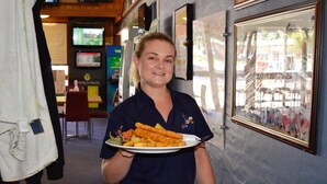 A person holding a plate with food, a counter, and a framed picture on the wall. - Brolga Hotel Motel (Coleambally)