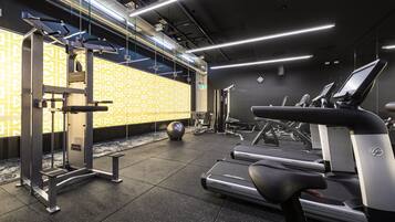 A gym with treadmills, a weight bench, and a wall with a geometric pattern.